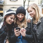 Drei Frauen sehen auf ein Smartphone (c) TINA Vienna/ shutterstock