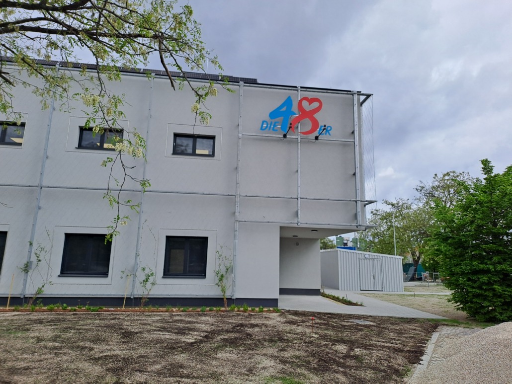 Ein weißer, zweigeschossiger Neubau mit 48er Logo